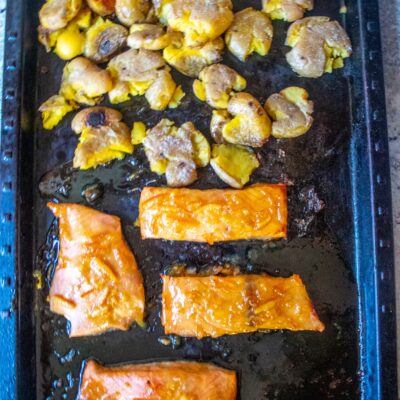 Orange marmalade and maple syrup "candy" salmon filets, served alongside creamy smashed potatoes. A great sheet pan meal!
