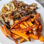 Herb crusted skirt steak with fresh cilantro and parsley, with a side of crisp-edged roasted sweet potatoes and slow-cooked onions.